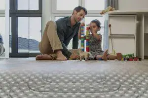 "Sıcak yerden ısıtma sistemi üzerinde oyun oynayan bir baba ve çocuğu. Bu sistem, çocuklar için konforlu ve güvenli bir zemin sunar."Altyazı ve Başlık Önerileri